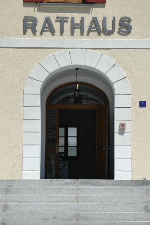 Eingangsportal des Rathaus' Neuhaus am Inn. Direkt hinter der Tür beginnt die Ausstellung: Wer was im Rathaus zu tun hat, geht an den Exponaten vorbei.